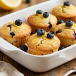 Fluffy air fryer mini muffins filled with blueberries and topped with fresh berries in a baking dish