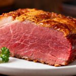 Tender air fryer corned beef with a juicy pink center and crispy seasoned crust served on a plate