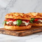 Juicy air fryer pizza burgers topped with melted mozzarella, pizza sauce, and fresh basil on toasted buns