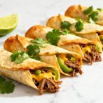 Crispy air fryer shredded beef taquitos filled with seasoned beef, melted cheese, and peppers