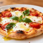Mini air fryer pizza topped with melted mozzarella cheese, cherry tomatoes, basil, and tomato sauce