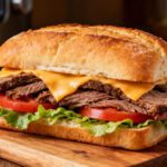 Air fryer roast beef sandwich loaded with tender sliced beef, melted cheese, lettuce, and tomato on a crusty roll