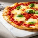 Air fryer tortilla wrap pizza with melted mozzarella cheese, tomato sauce, and fresh basil on a crispy tortilla crust