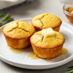 Golden air fryer cornbread muffins topped with melting butter and drizzled with honey