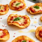 Crispy air fryer pizza chips topped with melted cheese, tomato sauce, and fresh basil