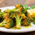 Crispy air fryer broccoli with golden roasted edges, tender centers, and fresh lemon wedges