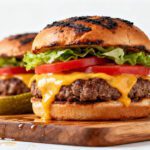 Juicy air fryer ground beef burgers topped with melted cheddar cheese, lettuce, and tomato on toasted buns