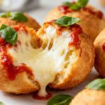 Crispy air fryer pizza balls stuffed with melted mozzarella cheese and topped with pizza sauce and basil