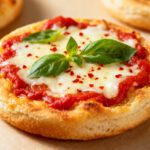 Air fryer English muffin pizza topped with melted mozzarella cheese, tomato sauce, and fresh basil