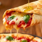 Air fryer pizza wrap filled with melted mozzarella cheese, pizza sauce, and fresh basil in a crispy tortilla