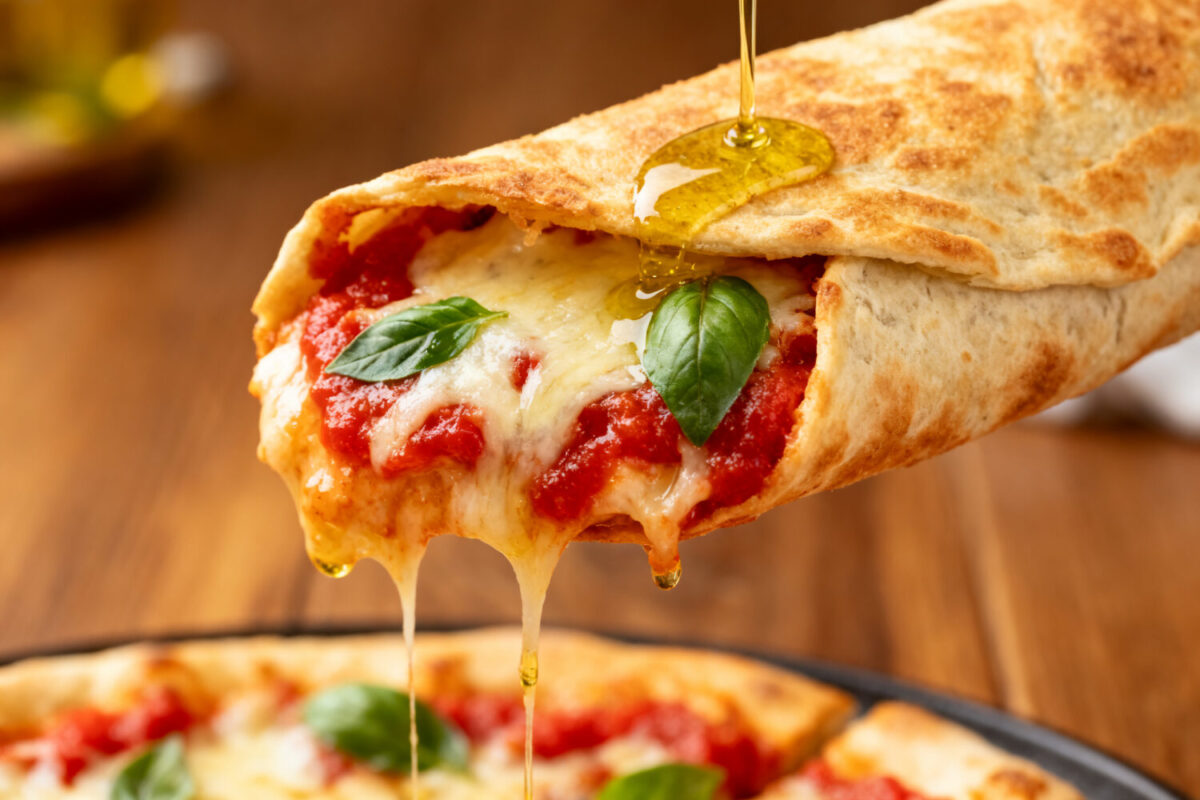Air fryer pizza wrap filled with melted mozzarella cheese, pizza sauce, and fresh basil in a crispy tortilla