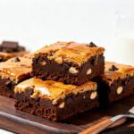 Fudgy air fryer protein brownies packed with chocolate chips and nuts, stacked on a wooden board