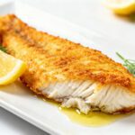 Healthy air fryer cod with a crispy golden coating, flaky white fish, and fresh lemon wedges