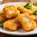 Crispy air fryer cod nuggets with a golden crunchy coating, flaky fish, and fresh lemon wedges
