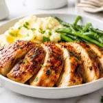 Sliced grilled chicken breast served with mashed potatoes and green beans
