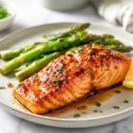 Maple glazed salmon served with asparagus and lemon on a dinner plate