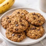 Plate of banana oatmeal chocolate chip cookies with ripe bananas and oats on a marble countertop