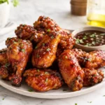 Crispy air fryer chicken wings coated in sticky barbecue sauce served on a plate with dipping sauce