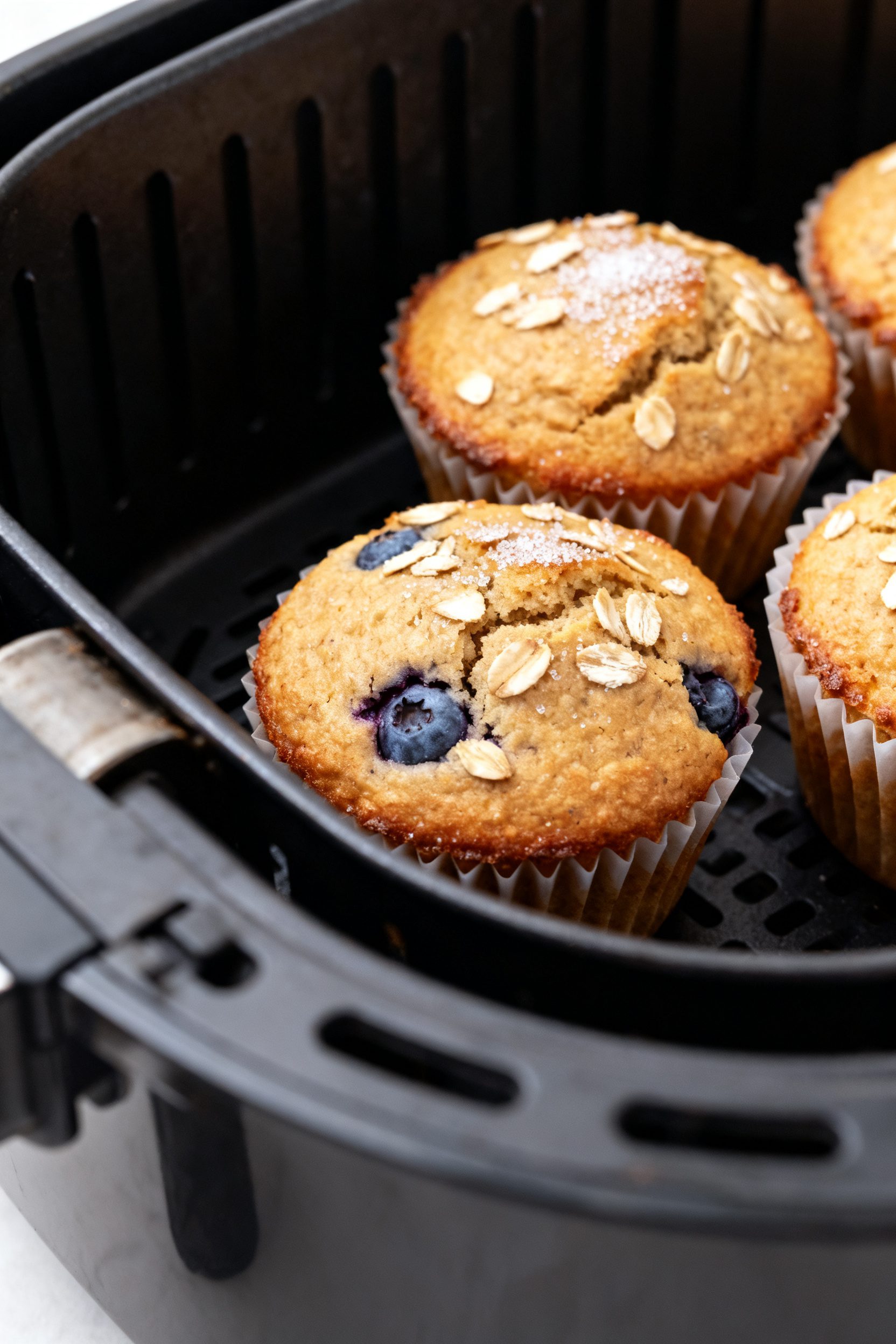 Close-up detail: Freshly air-fried oatmeal muffins still in silicone cups inside an air fryer basket