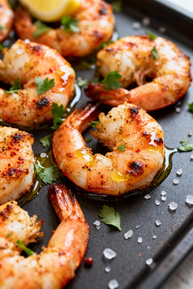 Close-up detail: Juicy air fryer grilled shrimp just out of the basket, lightly charred edges with v