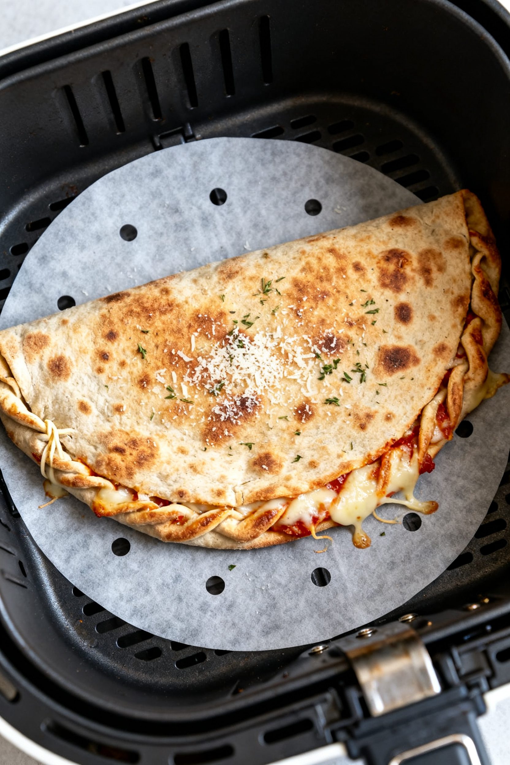 Cooking process: Air fryer basket shot at mid-cook, seam-side-down pizza wrap flipped halfway, surfa