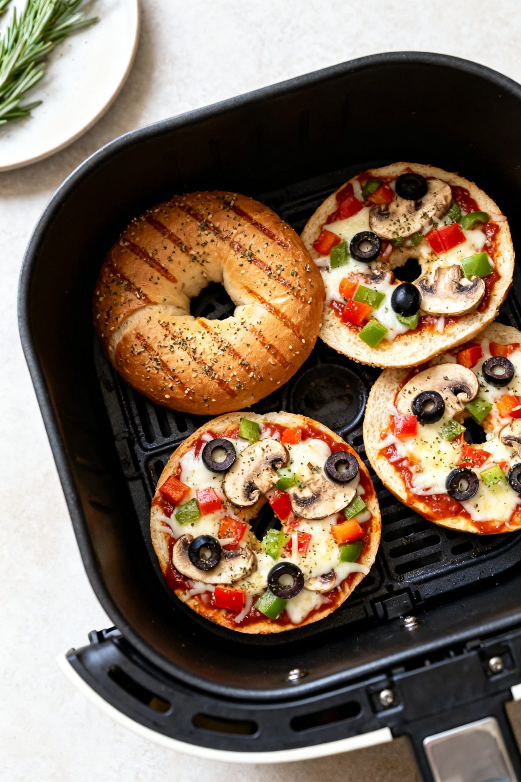 Cooking process: Overhead shot of bagel halves in the air fryer mid-cook at 375°F—pre-toasted, sa