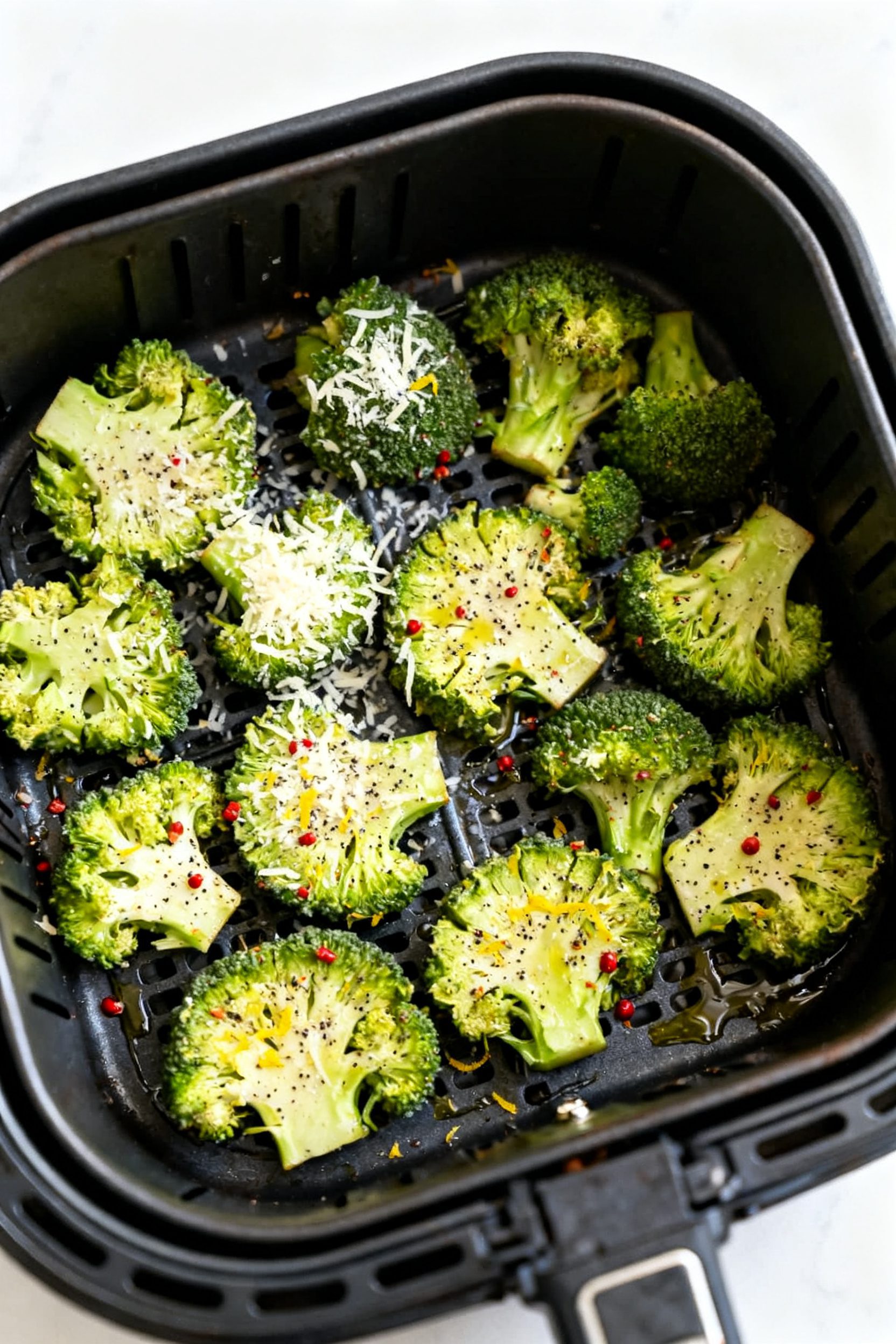 Cooking process: Overhead shot of smashed broccoli florets arranged in a single layer in an air frye