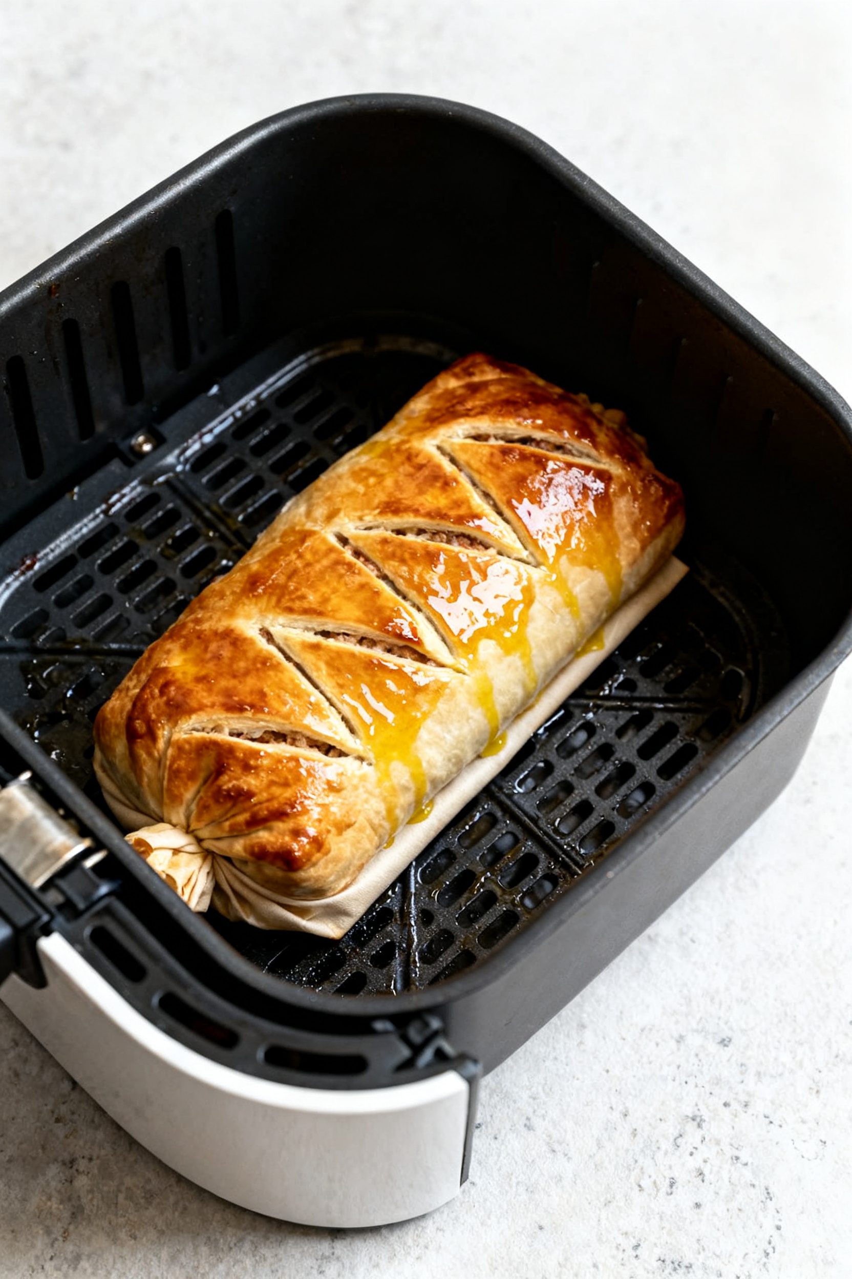 Cooking process: Overhead shot of the fully wrapped Wellington seam-side down in an open, preheated