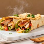 Air fryer chicken wraps filled with juicy chicken, fresh lettuce, tomatoes, and a savory sauce in crispy tortillas