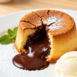 Molten air fryer lava cake with a warm gooey chocolate center, powdered sugar, and vanilla ice cream