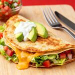 Air fryer crunch wrap filled with seasoned beef, melted cheese, lettuce, tomatoes, avocado, and creamy sauce in a crispy tortilla