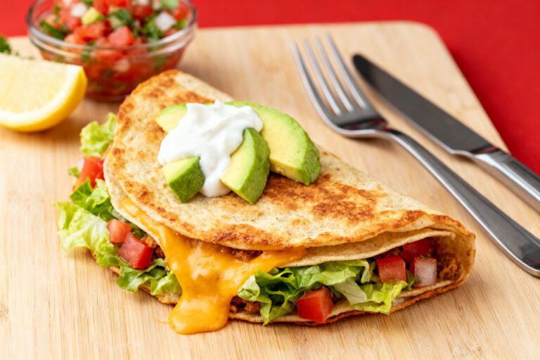 Air fryer crunch wrap filled with seasoned beef, melted cheese, lettuce, tomatoes, avocado, and creamy sauce in a crispy tortilla