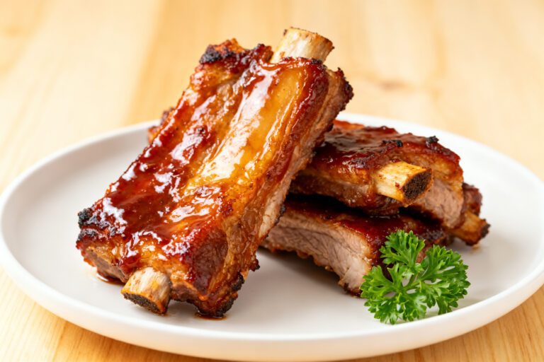 Air fryer barbecue pork ribs glazed with smoky sauce and served with pickles, coleslaw, and extra barbecue sauce