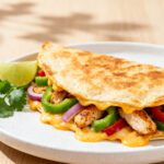 Easy air fryer quesadilla with juicy chicken, melted cheese, bell peppers, and onions in a crispy golden tortilla