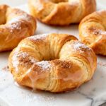 Air fryer crescent roll donuts with flaky buttery layers, sweet glaze, and a dusting of powdered sugar