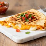 Air fryer cheese quesadilla with gooey melted cheese, crispy grilled tortilla, and fresh tomato garnish
