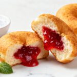 Air fryer jelly donuts with a soft fluffy texture and sweet strawberry jelly filling bursting from the center