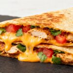Copycat air fryer Taco Bell quesadilla with juicy chicken, melted cheese, fresh tomatoes, cilantro, and crispy golden tortillas
