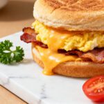 Frozen air fryer breakfast sandwich with fluffy eggs, crispy bacon, melted cheddar cheese, and a toasted English muffin