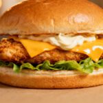 Homemade air fryer chicken sandwich with crispy fried chicken, melted cheddar cheese, fresh lettuce, and creamy sauce on a soft toasted bun.