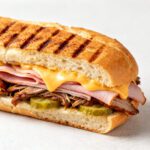 Air fryer Cuban sandwich with roasted pork, ham, melted cheese, and pickles on a toasted pressed roll with crispy grill marks.
