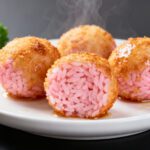 Air fryer pink rice balls with a crispy golden breadcrumb coating, served on a white plate and filled with vibrant pink rice.