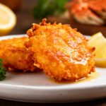 Air fryer crab crunchies with a crispy golden breadcrumb coating, served on a plate with lemon wedges and fresh parsley garnish.