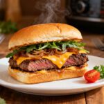 Air fryer steak sandwich with juicy sliced steak, melted cheddar cheese, caramelized onions, and fresh arugula on a toasted sandwich bun.