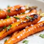 Air fryer roasted carrots caramelized until tender, topped with coarse sea salt and fresh herbs, served as a simple and flavorful side dish.