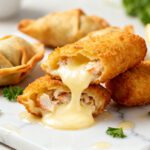 Air fryer crab rangoon mozzarella sticks with a crispy golden breadcrumb coating, filled with creamy crab and melted mozzarella cheese, served with lemon wedges and fresh parsley.