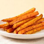 Air fryer crispy carrot fries seasoned with spices and roasted until golden brown, served on a white plate with crispy edges and tender centers.
