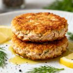 Air fryer keto tuna patties with a crispy golden crust, flaky tuna filling, fresh dill, and lemon wedges, served as a low carb high protein meal.