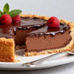 Air fryer chocolate cheesecake with a rich and creamy chocolate filling, smooth chocolate ganache topping, fresh raspberries, and a buttery cookie crust.