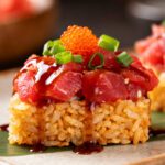 Air fryer crispy rice spicy tuna topped with diced tuna, spicy sauce, green onions, and fish roe, served on crispy golden rice squares.
